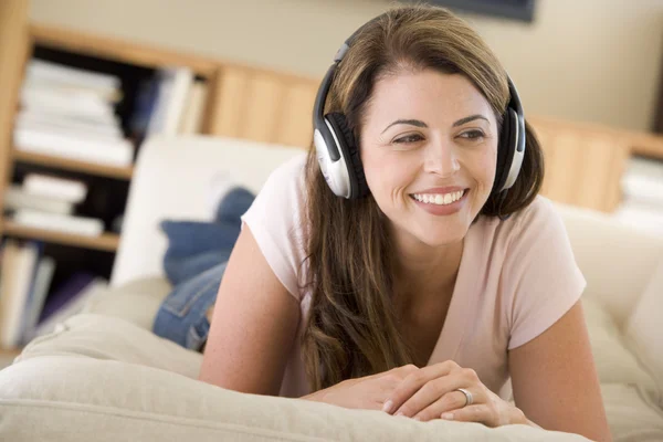 Женщина в гостиной слушает улыбающиеся наушники — стоковое фото