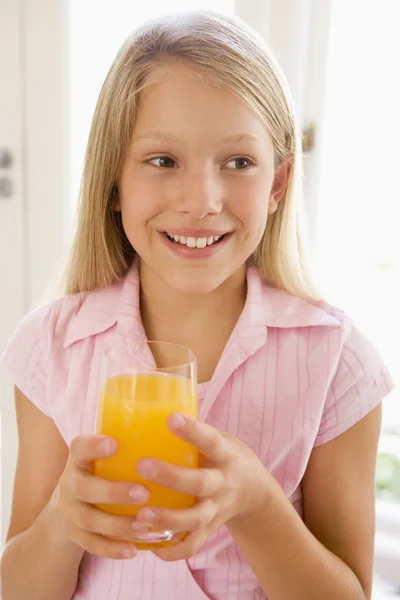 Junges Mädchen drinnen trinkt lächelnd Orangensaft — Stockfoto