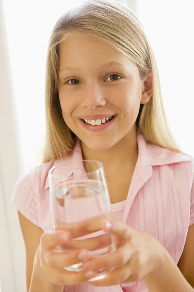 Young girl indoors drinking water smiling — Stock Photo, Image