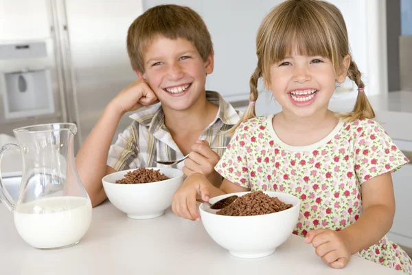 Dos niños pequeños en la cocina comiendo cereal sonriendo —  Fotos de Stock