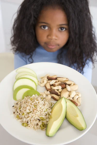 年轻女孩在厨房里吃大米水果和坚果 — 图库照片