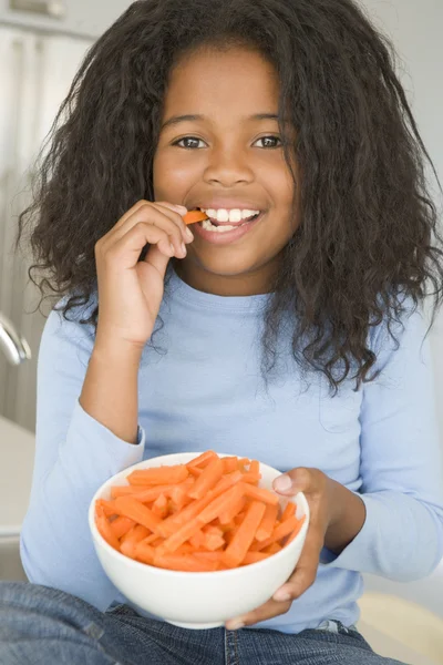 Havuç yemek mutfakta genç kız gülümseyerek yapışıyor — Stok fotoğraf