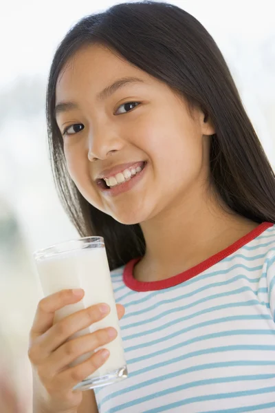 Νεαρό κορίτσι σε εσωτερικούς χώρους, πίνοντας γάλα χαμογελώντας — Φωτογραφία Αρχείου