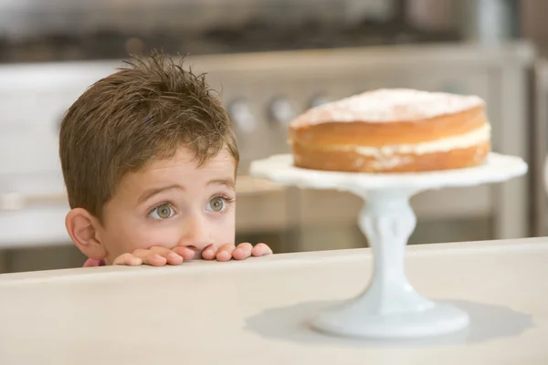 憧憬地盯着蛋糕在家里的男孩 — 图库照片