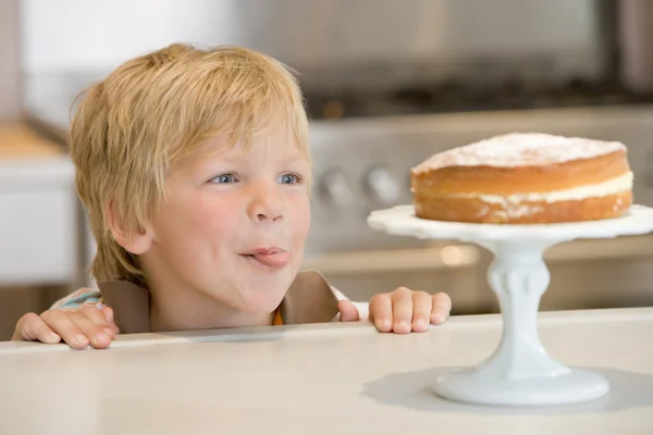 Jovem na cozinha olhando para bolo no balcão — Fotografia de Stock