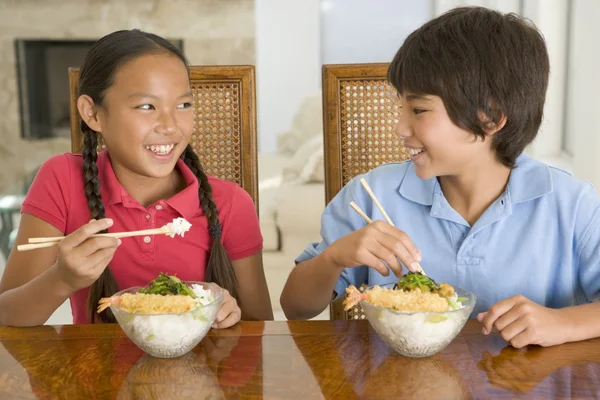 Двое маленьких детей едят китайскую еду в столовой, улыбаясь — стоковое фото