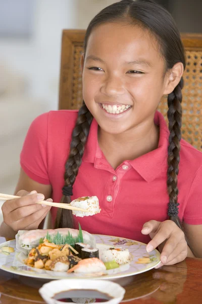 Молодая девушка в столовой ест китайскую еду улыбаясь — стоковое фото