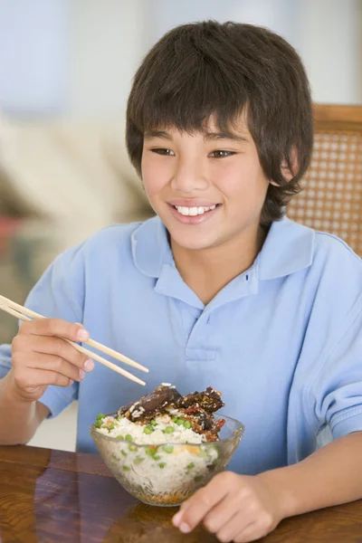 Ung pojke i matsalen äta kinesisk mat leende — Stockfoto