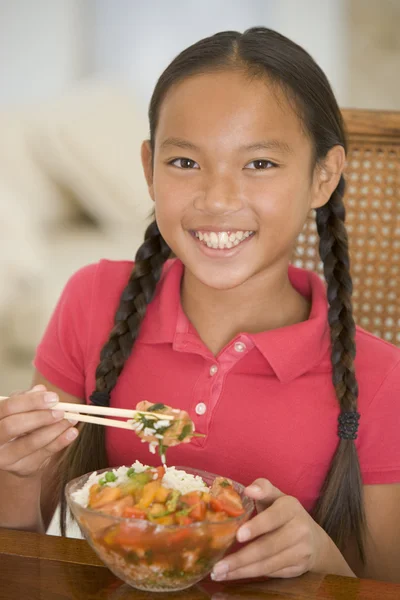 Молодая девушка в столовой ест китайскую еду улыбаясь — стоковое фото
