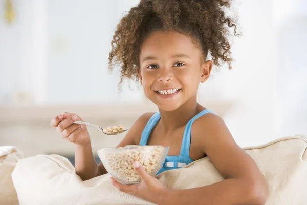年轻的女孩吃麦片在客厅里微笑 — 图库照片
