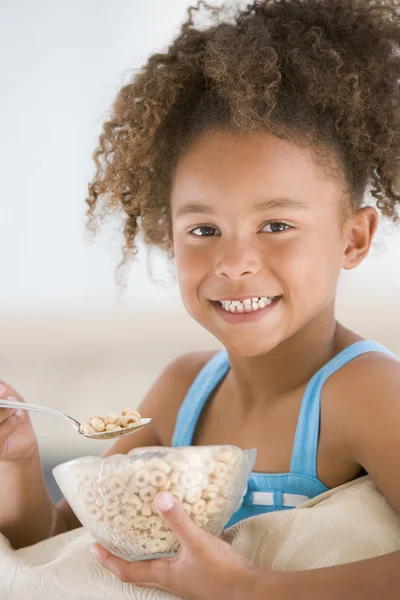 Chica joven comiendo cereal en la sala de estar sonriendo — Foto de Stock