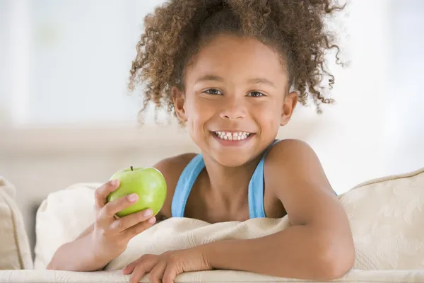 Ung Flicka Äta Äpple Vardagsrummet Leende — Stockfoto