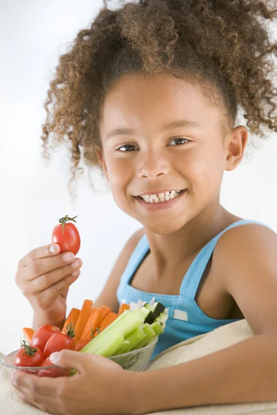 Молода дівчина їсть миску з овочами у вітальні посміхається — стокове фото