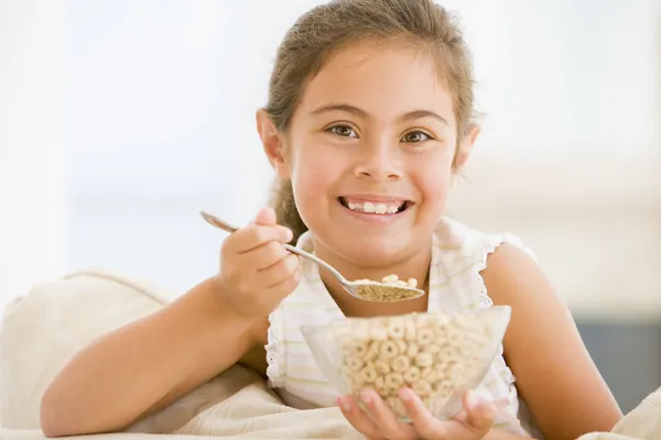 年轻的女孩吃麦片在客厅里微笑 — 图库照片