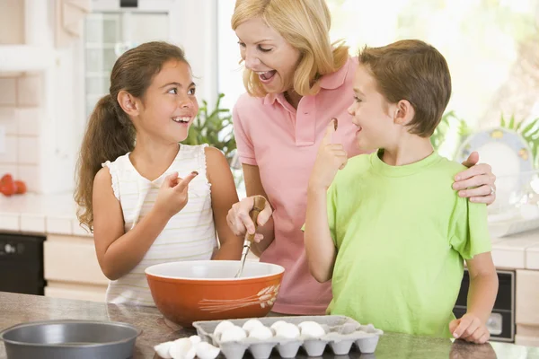 Mujer y dos niños en la cocina horneando y sonriendo —  Fotos de Stock