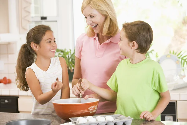 女人和两个孩子在厨房里烘烤和微笑 — 图库照片