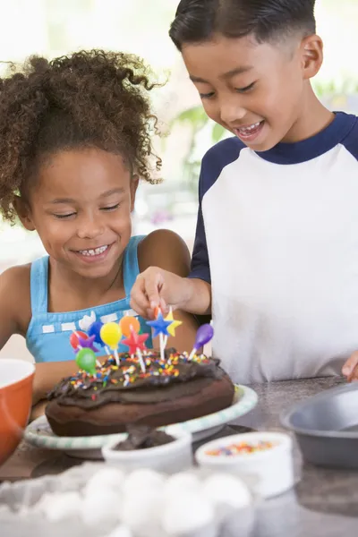 Dos niños en la cocina con pastel de cumpleaños sonriendo — Foto de Stock