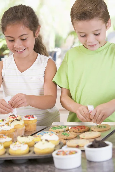 Dos niños en cocina decorando galletas sonriendo —  Fotos de Stock