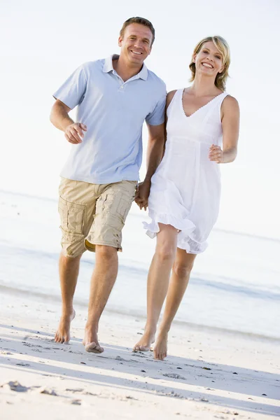 手を繋いでいる笑顔とビーチでのカップル ロイヤリティフリーのストック画像