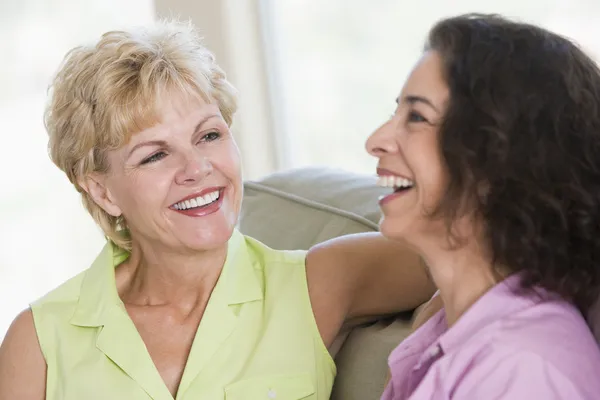 Two women in living room talking and smiling — Stock Photo, Image