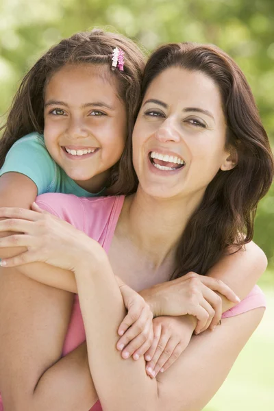 拥抱户外微笑的女人和年轻女孩 免版税图库图片