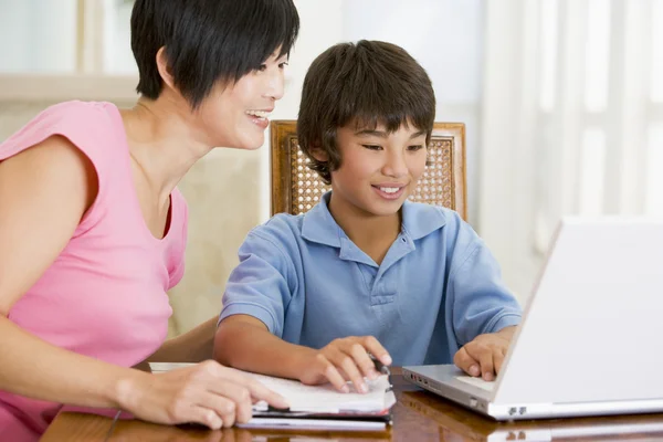 Mulher ajudando menino com laptop fazer lição de casa na sala de jantar s — Fotografia de Stock