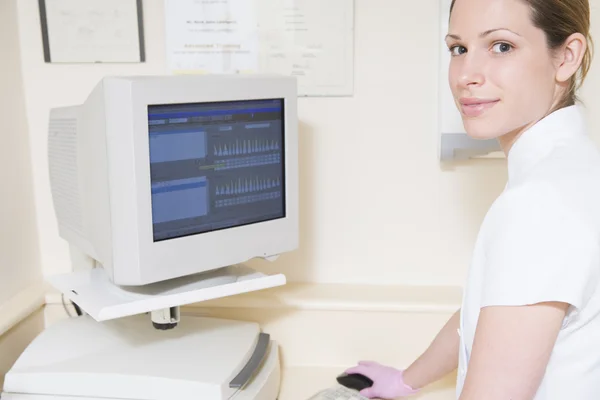 Dental assistant using computer smiling — Stock Photo, Image