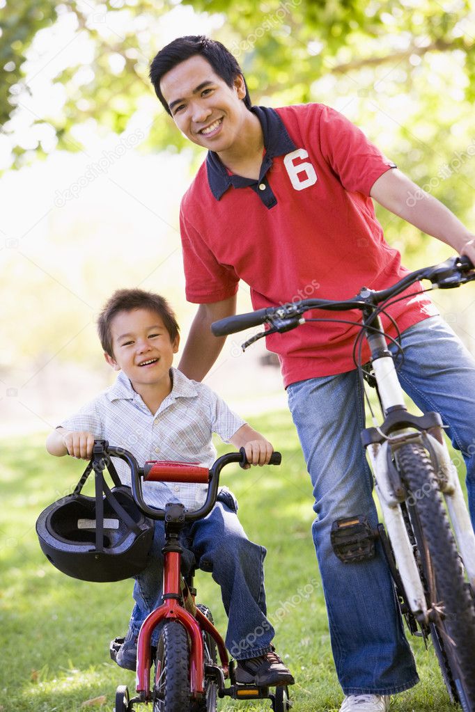 Man and young boy on bikes outdoors smiling — Stock Photo