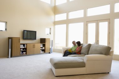 Couple reading book in living room smiling clipart