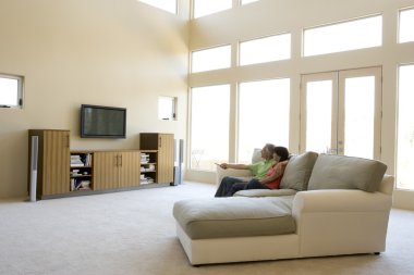 Couple in living room watching television clipart