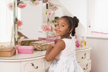 Young girl sitting at mirror in bedroom smiling clipart