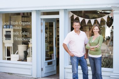 Couple standing in front of organic food store smiling clipart