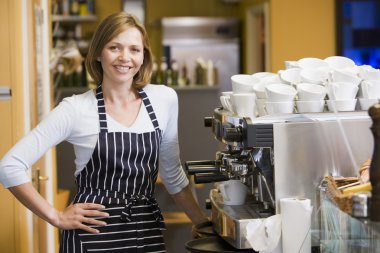 Woman making coffee in restaurant smiling clipart