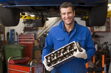 Mechanic holding car part smiling clipart