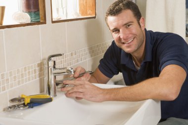 Plumber working on sink smiling clipart