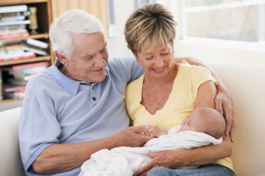 Grandparents in living room with baby smiling clipart