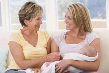 Grandmother and mother in living room with baby smiling clipart