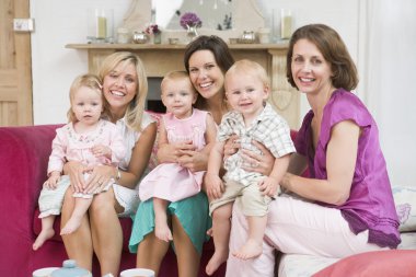 Three mothers in living room with babies smiling clipart