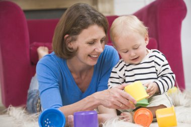 Mother in living room playing with baby smiling clipart