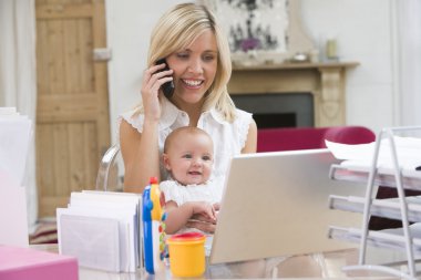 Mother and baby in home office with laptop and telephone clipart