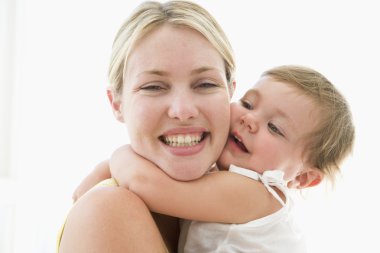 Mother and baby indoors hugging and smiling clipart