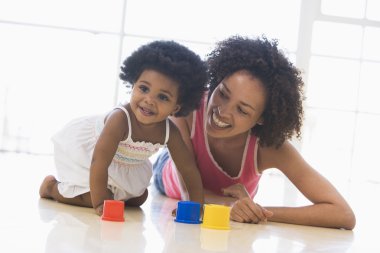 Mother and daughter indoors playing and smiling clipart