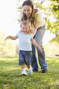 Mother and daughter playing outdoors smiling clipart