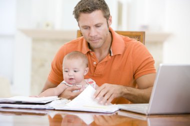 Father and baby in dining room with laptop clipart
