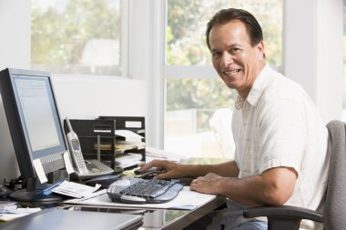 Man in home office at computer smiling clipart