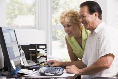 Couple in home office at computer smiling clipart