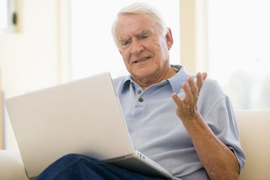 Man in living room with laptop clipart