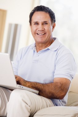 Man in living room with laptop smiling clipart