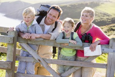 Family on cliffside path leaning on fence and smiling clipart