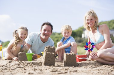 Family on beach making sand castles smiling clipart